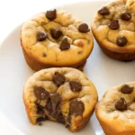 Freshly baked flourless peanut butter banana muffins on a wire rack, golden brown with melted chocolate chips.