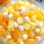 Serving Sunshine Salad in bowls, garnished with mint and shredded coconut.